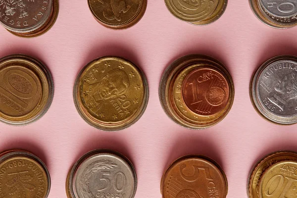 Vue du dessus des piles de pièces de divers pays sur rose — Photo de stock