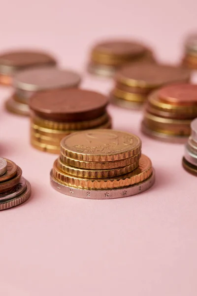 Close-up shot of stacks of coins from various countries on pink — Stock Photo