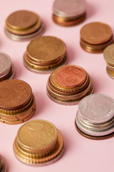 Close-up shot of stacks of coins from different countries on pink — Stock Photo