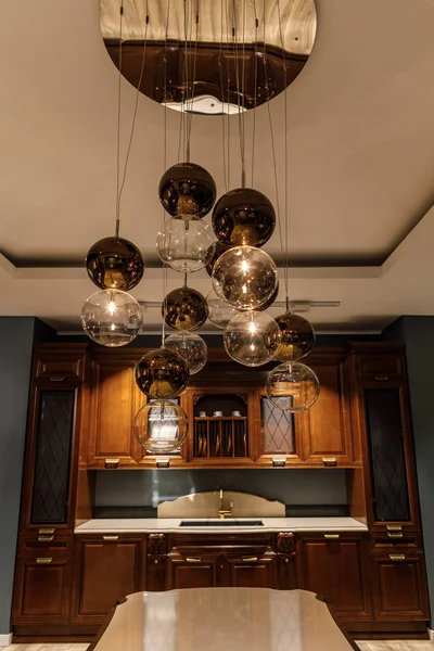 Lámpara de araña esférica brillante sobre elegante mostrador de madera en la cocina - foto de stock