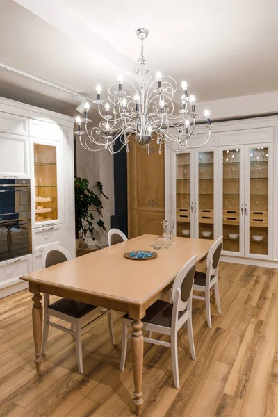 Elegante cocina con elegante mesa de madera y lámpara de araña - foto de stock