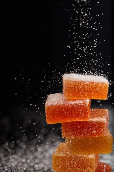 Closeup shot of sugar falling on jelly candies on black background — Stock Photo