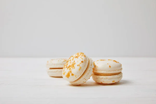 Primer plano de tres macarons sobre mesa de madera blanca - foto de stock