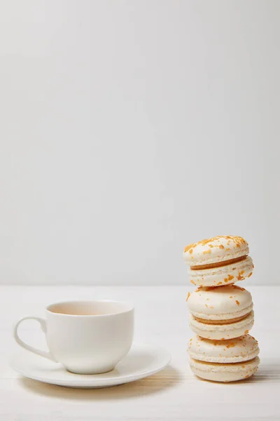 Primo piano colpo di tazza di caffè e pila di macaron su tavolo di legno bianco — Foto stock