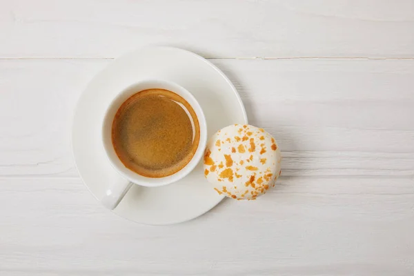 Vista superior de macaroon e xícara de café na mesa de madeira branca — Fotografia de Stock