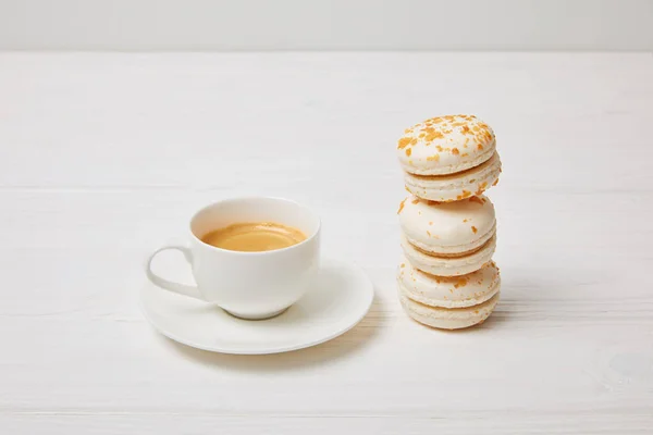 Nahaufnahme von Kaffeetasse und Stapel Makronen auf weißem Holztisch — Stockfoto