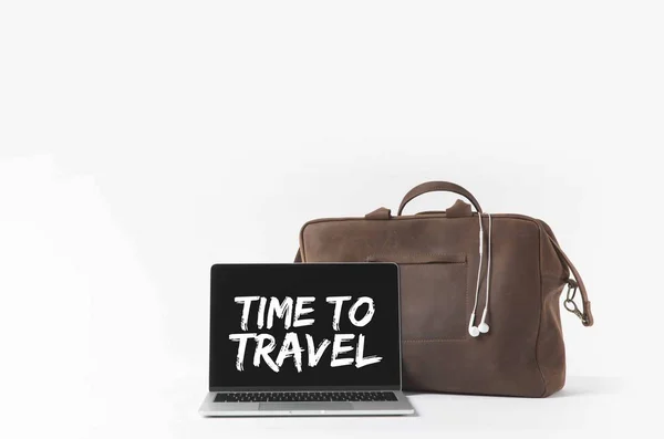 Ordinateur portable avec Time to travel inspiration à l'écran et sac élégant avec écouteurs, isolé sur blanc — Photo de stock