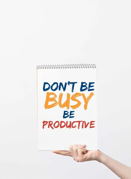 Vista parcial de la mujer sosteniendo cuaderno de bocetos con Dont be Busy ser letras productivas en la mano, aislado en blanco - foto de stock