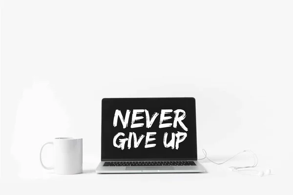 Laptop with Never give up inspiration on screen, earphones and white mug, isolated on white — Stock Photo
