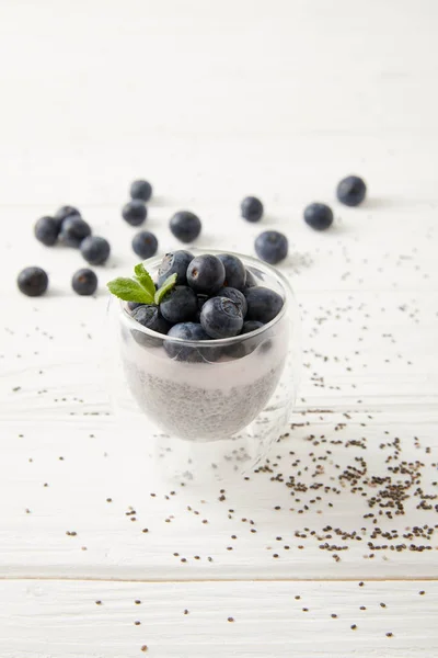 Close up view of sweet chia seed pudding with blueberries and mint on white wooden surface — Stock Photo