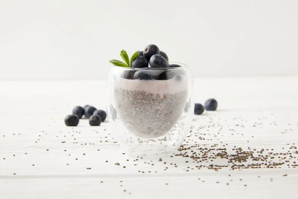 Close up view of sweet chia seed pudding with blueberries and mint on white wooden surface — Stock Photo