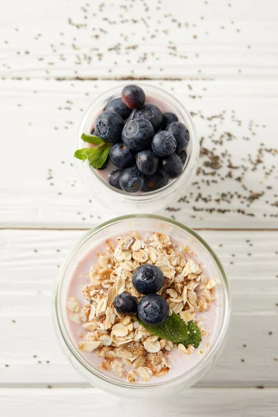 Flart lay with arranged chia puddings with fresh blueberries, oatmeal and mint on white wooden tabletop — Stock Photo