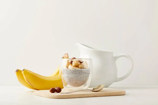 Vue rapprochée du délicieux pudding aux graines de chia aux bananes et noisettes sur table blanche — Photo de stock