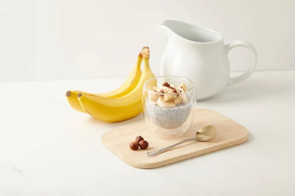 Vista de perto do saboroso pudim de semente de chia com bananas e avelãs na mesa branca — Fotografia de Stock