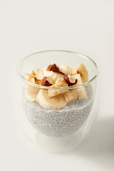Крупним планом вид смачного пудингу насіння Чіа з шматочками банана та лісових горіхів на білому столі — стокове фото