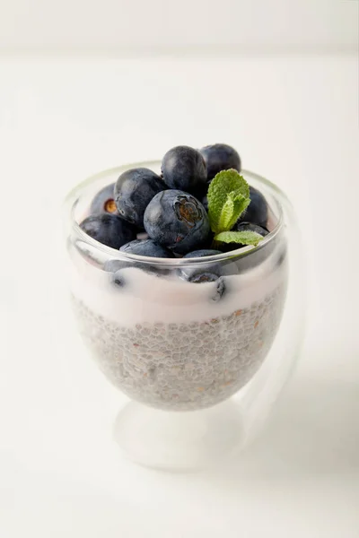 Close up view of chia seed pudding with blueberries and mint on white surface — Stock Photo
