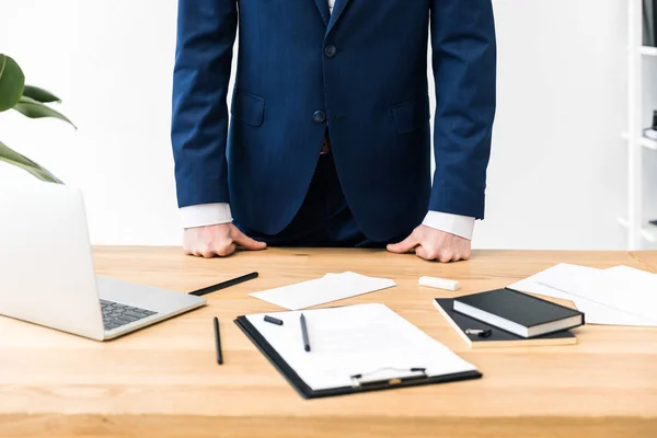 Teilansicht des Geschäftsmannes am Arbeitsplatz mit Notizbuch, Notizblock und Laptop im Büro — Stockfoto