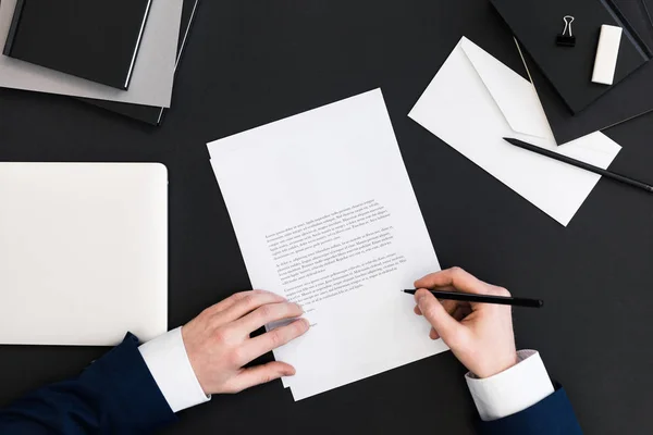 Teilansicht eines Geschäftsmannes im Anzug beim Unterschreiben von Papieren am Arbeitsplatz mit Laptop — Stockfoto