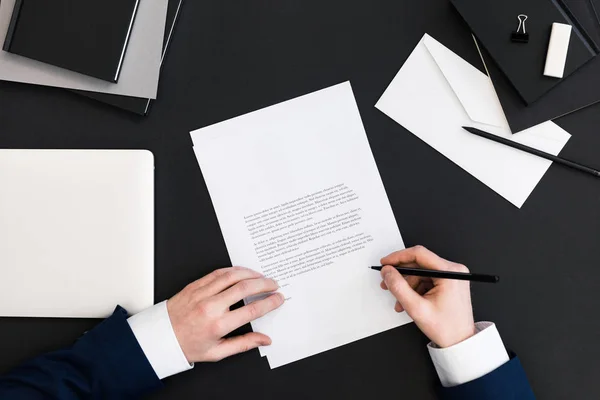 Partial view of businessman in suit signing papers at workplace with laptop — Stock Photo