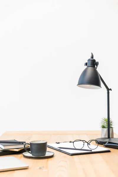 Close up view of cup of coffee, eyeglasses, documents and lamp at workplace in office — Stock Photo