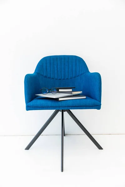 Nahaufnahme von Laptop, schwarzen Notizbüchern und Brillen auf blauem Stuhl auf weißem Hintergrund — Stockfoto