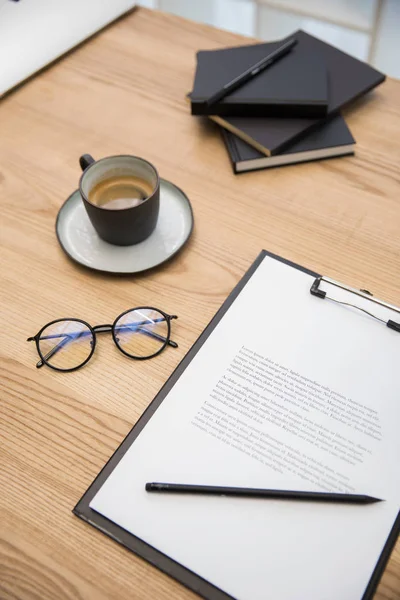 Vista de perto de xícara de café, óculos, documentos em mesa de madeira — Fotografia de Stock