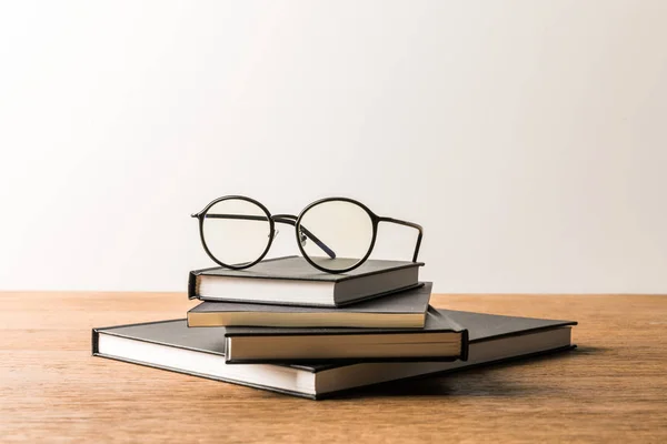 Close up view of pile of black notebooks and eyeglasses on wooden tabletop — Stock Photo