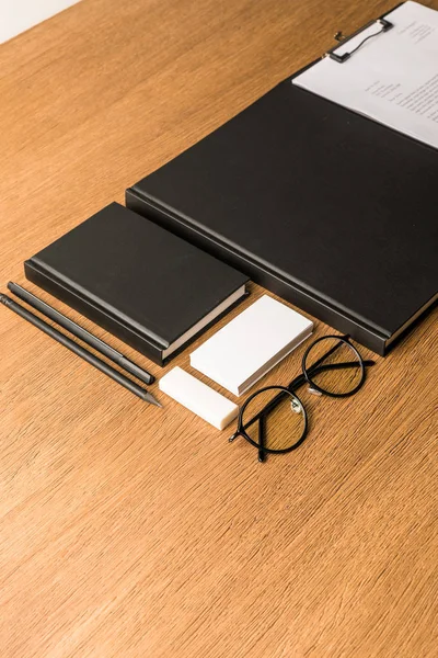 Close up view of black notebooks, eyeglasses and blank card at workplace — Stock Photo