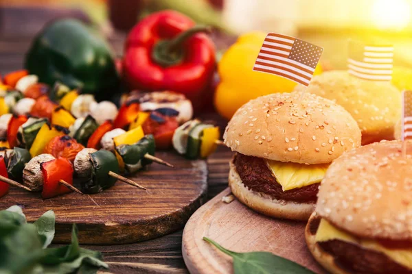 Hamburguesas con nosotros banderas cocinadas al aire libre en la parrilla - foto de stock