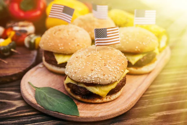 USA flags on hamburgers cooked outdoors on grill — Stock Photo