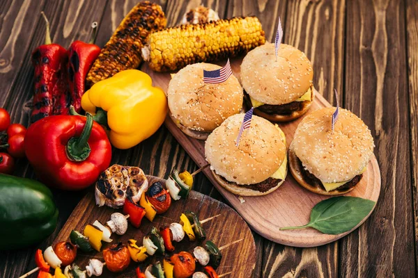 Independence day dinner with hamburgers and vegetables cooked outdoors on grill — Stock Photo