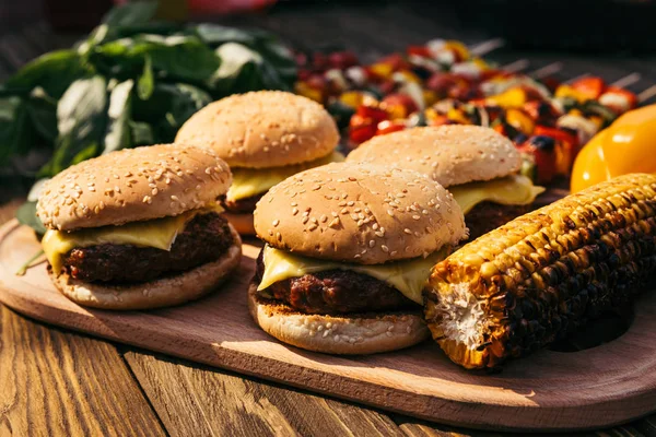 Hamburguesas y verduras calientes deliciosas a la parrilla para barbacoa al aire libre - foto de stock