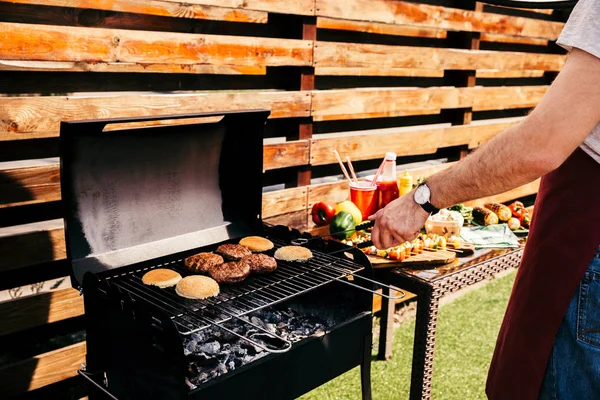 Чоловік готує м'ясні гамбургери на грилі для барбекю на відкритому повітрі — стокове фото