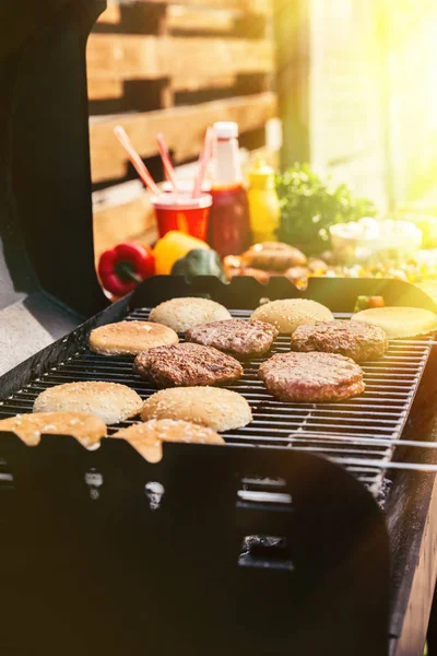 Buns and meat chops cooked outdoors on grill — Stock Photo