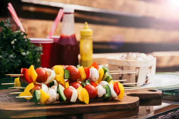 Vegetables on skewers with ketchup and mustard cooked outdoors — Stock Photo