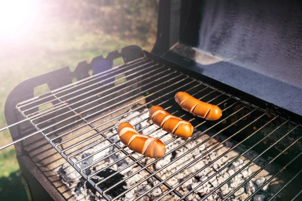 Cut sausages cooked outdoors on grill over fire — Stock Photo