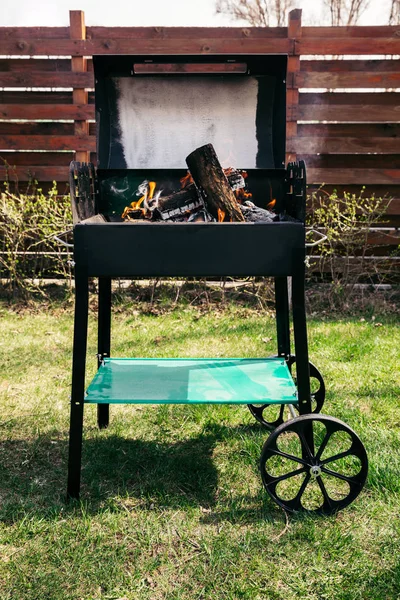 Metal outdoor grill with logs burning on fire — Stock Photo