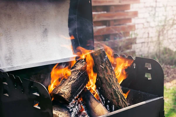 Fire over wooden logs in outdoors bbq — Stock Photo