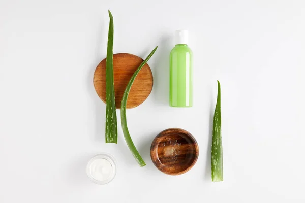 Top view of wooden bowl with aloe vera juice, organic cream and shower gel, aloe vera leaves on wooden slices — Stock Photo