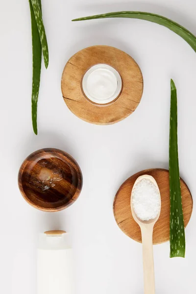 Top view of organic cream in container and spoon with salt on wooden slices, aloe vera leaves and wooden bowl with aloe vera juice — Stock Photo