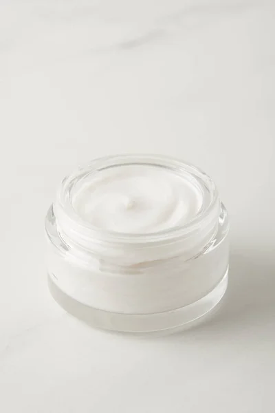 Closeup view of organic cream in container on marble tabletop — Stock Photo