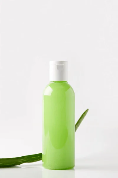 Vista close-up de gel de chuveiro orgânico em garrafa e folha de aloe vera na superfície branca — Fotografia de Stock