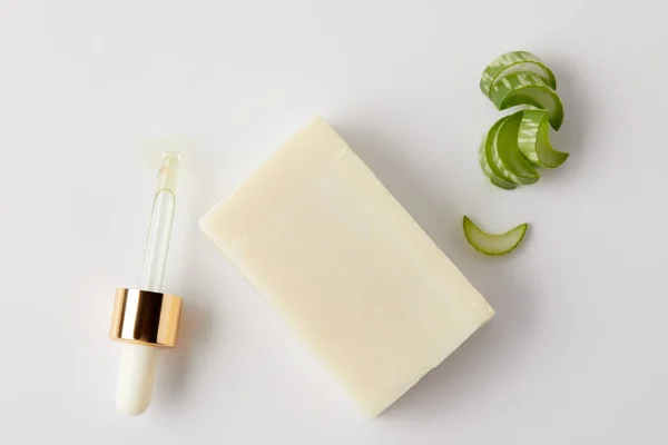 Elevated view of dropper, soap and aloe vera slices on white surface — Stock Photo