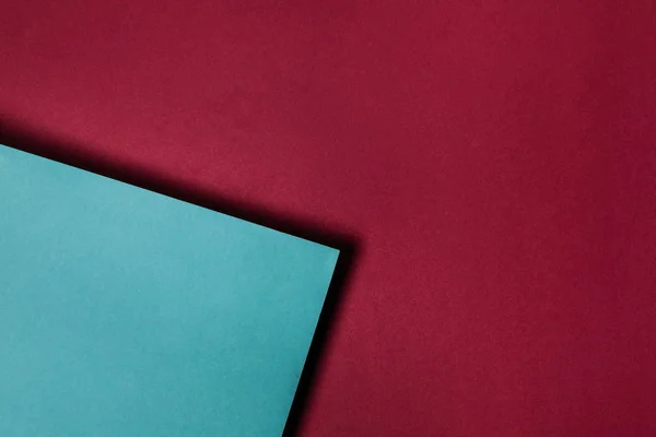 Turquoise paper sheet on maroon background — Stock Photo