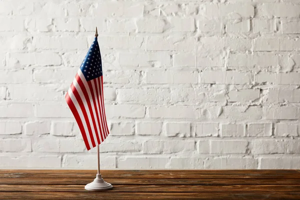 Соединенные Штаты Америки флагшток на деревянной поверхности против кирпичной стены — стоковое фото