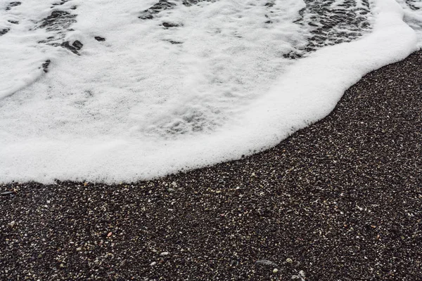 Espuma de mar en la playa de arena en la costa - foto de stock