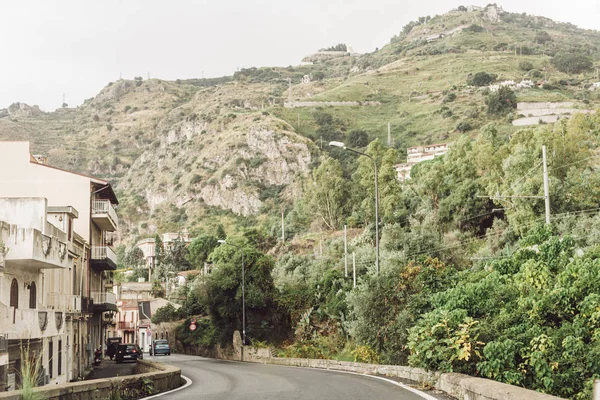 Bâtiments près de la route et les collines avec des arbres en italie — Photo de stock