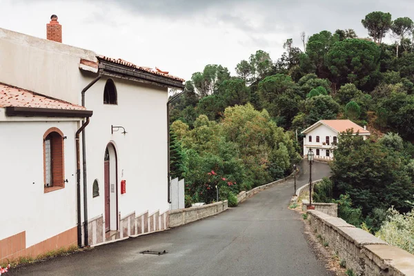 Pequeñas casas cerca de árboles verdes y carretera en italia - foto de stock
