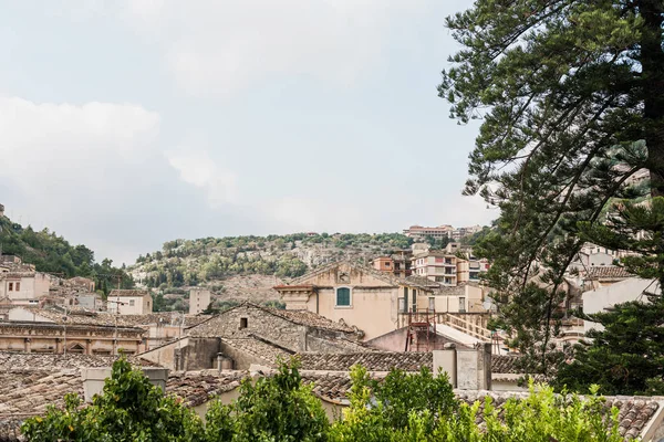 Pequenas casas perto de plantas verdes e árvores em modica, itália — Fotografia de Stock