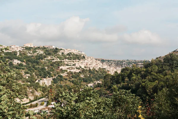 Sol en los techos de casas antiguas y árboles en ragusa, italia - foto de stock